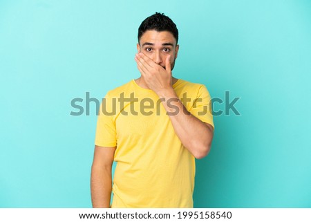 Young arab man isolated on blue background covering mouth with hand Royalty-Free Stock Photo #1995158540
