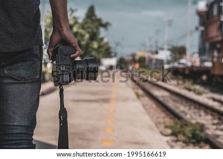 Tourists stand holding digital cameras near train tracks. concept of tourism and travel