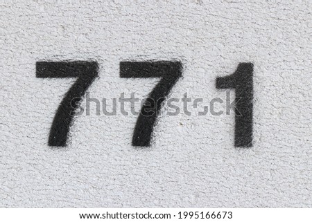 Black Number 771 on the white wall. Spray paint. Number seven hundred and seventy one.