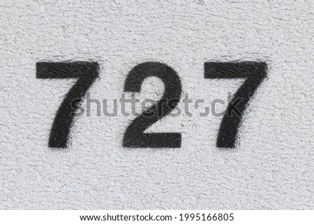 Black Number 727 on the white wall. Spray paint. Number seven hundred twenty seven.