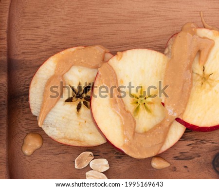 Top view of apple slices with peanut butter on wooden plate