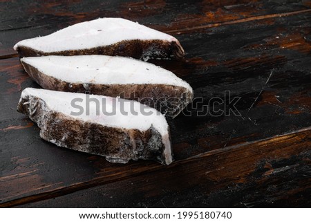 Halibut fish frozen steak set, on old dark  wooden table background, with copy space for text