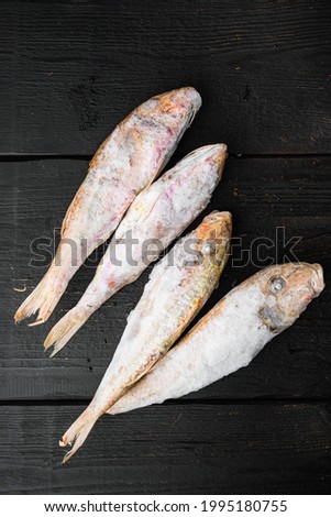 Frozen surmullet  fish set, on black wooden table background, top view flat lay