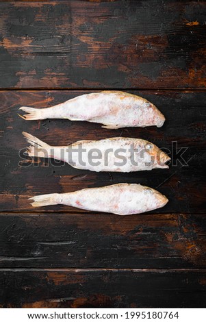 Frozen red mullet or barabulka raw fish set, on old dark  wooden table background, top view flat lay , with copy space for text