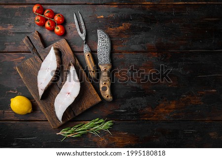 Raw steak of white fish set, with ingredients and rosemary herbs, on old dark  wooden table background, top view flat lay, with copy space for text