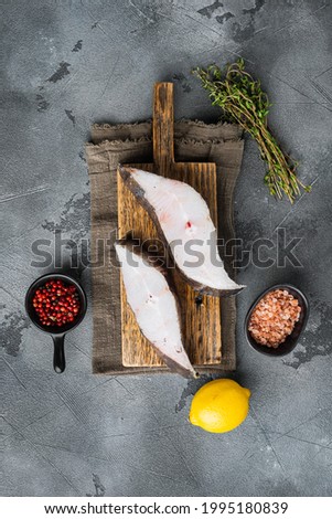 Sliced Halibut fish set, with ingredients and rosemary herbs, on gray stone table background, top view flat lay, with copy space for text
