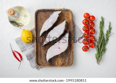 Raw halibut set, with ingredients and rosemary herbs, on white stone table background, top view flat lay