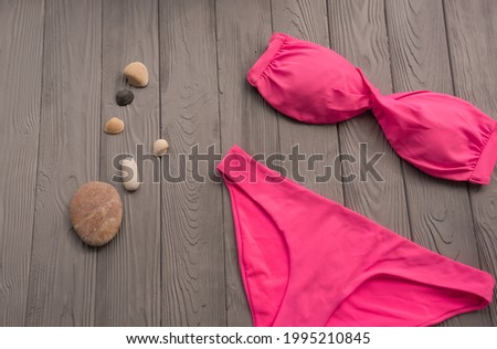 woman trending two-piece swimsuit beach pink swimwear fashion sunglasses. Summer background template mockup copy free space colorful composition sample text. Top view above grey wooden background.