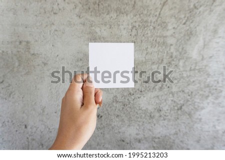 Hand holding white note paper.