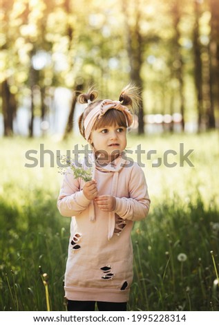 A little girl with a small bouquet of flowers in the park in the summer. Cute portrait. Vertical