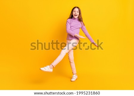 Full size photo of happy excited good mood little girl dancing enjoying free time isolated on yellow color background