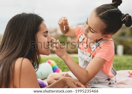 Cute little girl making up her big sister - Teenage girl enjoy day outdoor with little sister - Family love