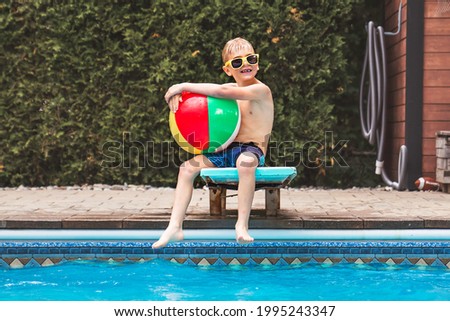 A child boy having fun in Pool on the summer time sit on springboard