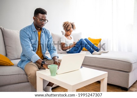 Millennial generation father working from home with small children while in quarantine isolation during the Covid-19 health crisis. Little girl on tablet computer. Horizontal indoors 