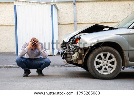 Young man driver in car accident holding his head near broken car on the road after car accident. Caucasian man facepalm holding head injury after accident Royalty-Free Stock Photo #1995285080
