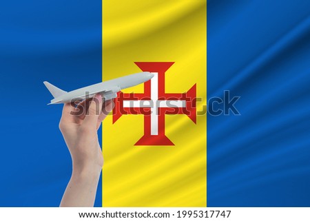 Airplane in hand with national flag of Madeira. Travel to Madeira.
