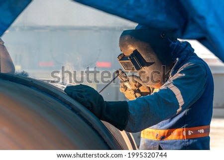 Welder is welding with shielded metal arc welding process with covered electrode to pipeline in the welder tent.