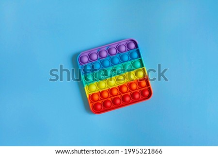 New popular silicone colorful pop It game in the form of rectangular isolated on a blue background. View in above. Anti-stress. Close-up of the popular children's toy pop It fidget. Copy space. Royalty-Free Stock Photo #1995321866