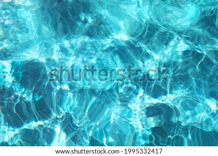 Turquoise blue rippled water surface of swimming pool. Summer vacations resort concept. Background of water ripple under bright sunny sky. Full frame texture. Banner with place for text.