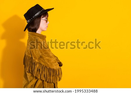 Photo of strong serious woman dressed cowboy clothes spectacles cap arms folded looking empty space isolated yellow color background