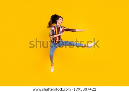 Full length body size photo girl in casual clothes jumping practising martial arts isolated bright yellow color background