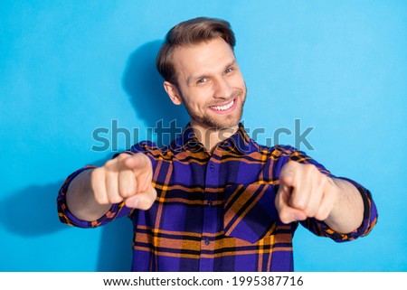 Portrait of attractive cool cheerful guy pointing forefingers at you isolated over vivid blue color background