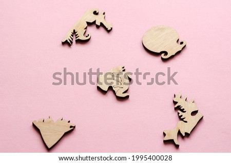 Wooden puzzle on a pink background. Puzzle pieces in the shape of animals and other complex shapes. Active leisure. Board games to develop logical thinking.