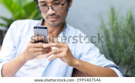 happy young man using smartphone during relaxing time at home focus on hand holding smartphone
