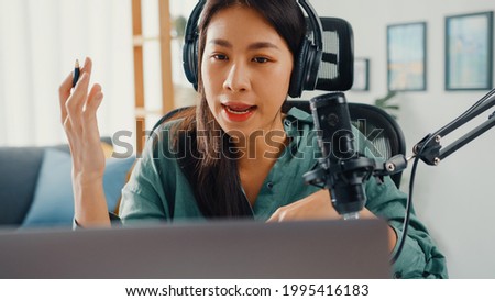 Happy asia girl record a podcast on her laptop computer with headphones and microphone talk with audience at her room. Female podcaster make audio podcast from her home studio, Stay at house concept.