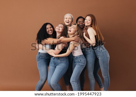 Six laughing women of a different race, age, and figure type. Group of multiracial females having fun against a brown background. Royalty-Free Stock Photo #1995447923