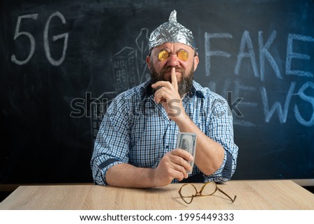stupid conspiracy theorist with bitcoin coins in his eyes and dollar bills in his hand closes his mouth with his finger.Secrets and fake news.Conspiracy theory. Cryptocurrency. Myths and Reality Royalty-Free Stock Photo #1995449333