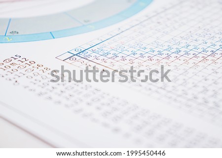 Modern astrologer's desktop. Astrological charts and tables with the coordinates of the planets, astrological symbols close-up.