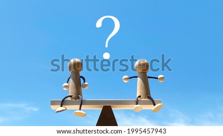Two dolls on a balance pole_blue sky background_question Royalty-Free Stock Photo #1995457943