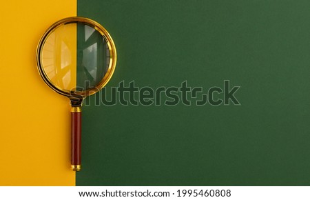 Golden magnifying glass or lens over green background.