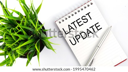 LATEST UPDATE - business concept text on the white notebook and glasses, pencil , green flowers