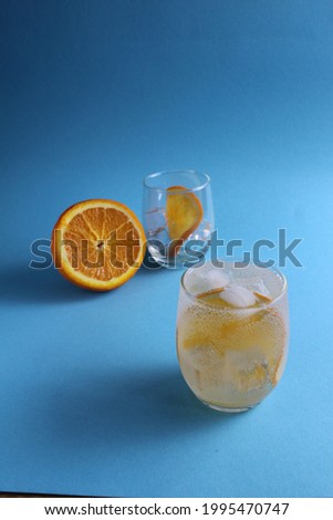 Step-by-step making of lemonade. Step 2. Pour the fruit orange with soda water. A glass of lemonade orange on a blue background with a place for text . close-up.