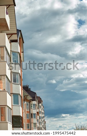Residential modern multi-story houses in front of cloudy blue sky. Copy space. Vertical photo.