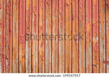 horizontal picture of old grey vertical planks with fading red and orange paint