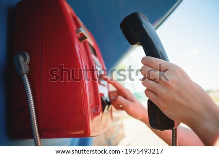 Woman is calling by the public payphone close up. Royalty-Free Stock Photo #1995493217