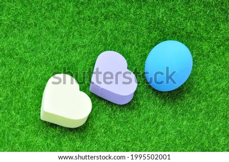 Heart made of sponge and Easter eggs on green grass.