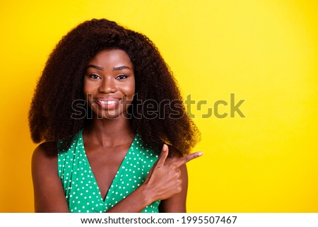 Photo portrait of woman curly hair in green top pointing finger empty space isolated vibrant yellow color background