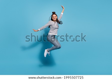 Full size profile side photo of young cheerful african girl happy positive smile have fun jump isolated over blue color background