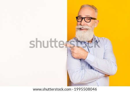Photo of positive beard aged man point advert wear spectacles blue shirt isolated on yellow color background
