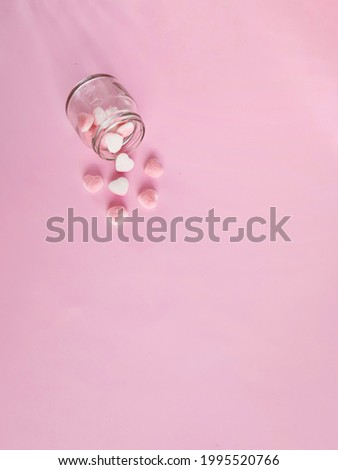 Heart-shaped candy sprinkles on pink background