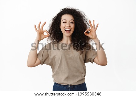 No problem. Smiling confident girl winking and showing OK okay gesture, approve something good, praise excellent choice, assuring everything under control, standing over white background