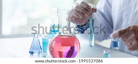 Young man scientist in gloves working on laboratory test of blue liquid in tube, chemistry science, medical biology experiment technology, pharmacy development solution. Close upbanner copy space
