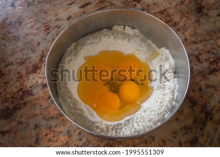 Flour and eggs in a metal bowl. Ready to be mixed for a delicious recipe.