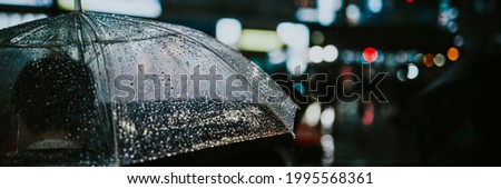 Man walking with a transparent umbrella in a city at night