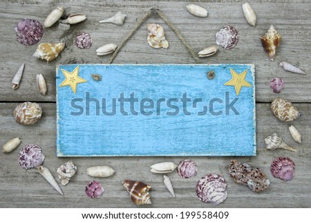 Blank blue sign with seashells hanging on rustic wooden background