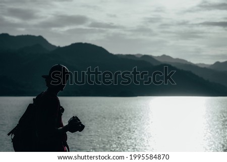 young teen Caucasian boy hipster man silhouette adult backpacker enjoying camera on beautiful landscape scenery view jungle mountains forest at Kanchanaburi water river lake dam, Thailand